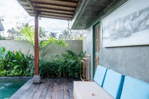 a porch with blue chairs and a swimming pool at The Asiki Sebatu in Tegalalang