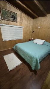 Un dormitorio con una cama en una habitación de madera. en Casa a Mano todo cercano, en Futrono