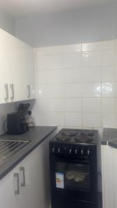 a kitchen with a black stove and white cabinets at Ayish in Birmingham