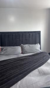 a bed with a black headboard and pillows on it at Ayish in Birmingham