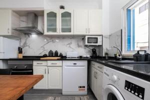 una cucina con armadi bianchi e lavastoviglie bianca di Cabanas Coastal Escape a Tavira