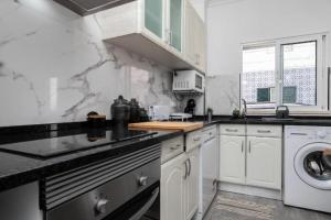 una cucina bianca con lavandino e lavatrice di Cabanas Coastal Escape a Tavira