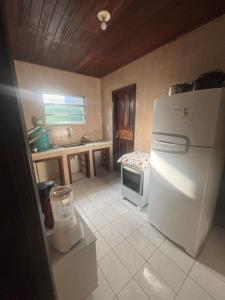 a kitchen with a white refrigerator and a stove at Casa da Gigi in Arraial do Cabo +5 photos