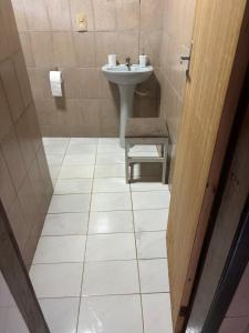 a bathroom with a sink and a toilet and a chair at Casa da Gigi in Arraial do Cabo