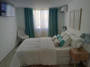 ein Schlafzimmer mit einem großen weißen Bett und einem Stuhl in der Unterkunft L'Etage 1 2 in Pointe-à-Pitre