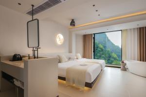 Un dormitorio blanco con una cama y una ventana grande. en THAT MAY Hotel, en Yangshuo