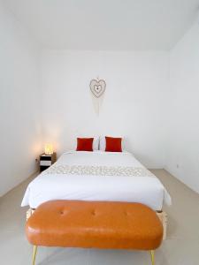 ein Schlafzimmer mit einem weißen Bett und einer orangefarbenen Bank in der Unterkunft Yan Loft in Uluwatu