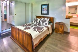 a bedroom with a large bed with a wooden frame at Tropical cocoon with 2 bedrooms in Papeete