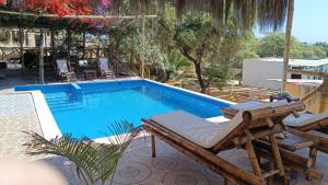 a swimming pool with a deckchair and a chaise lounge next to it at Villa Naylamp Loft 3 playa pocitas in Puerto Máncora