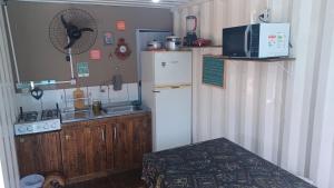 a small kitchen with a refrigerator and a microwave at Hospedagem Tribos Livres in Torres