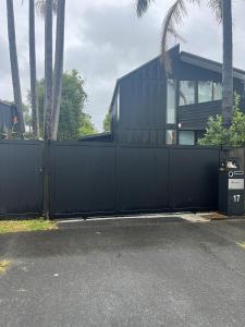 ein schwarzer Zaun vor einem Haus mit Palmen in der Unterkunft Myrtle St Guesthouse in Auckland