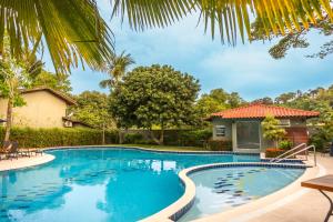 a swimming pool in front of a house at Casa Cajueiro - Arraial Dajuda - limpeza diária inclusa no preço para sua maior comodidade - localização excepcional em frente ao Eco Parque e poucos passos da Praia dos Pescadores in Arraial d'Ajuda