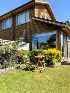 a table and a chair in front of a house at Whispering Pines in Kaihinu