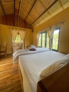 1 cama blanca grande en una habitación con ventanas en Farm House, en Phu Quoc