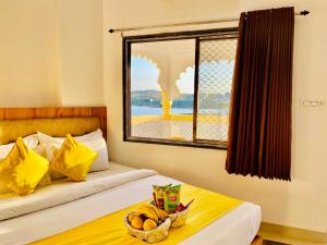 a bedroom with two beds with a basket of fruit on a table at Hotel Vallabh at Pichola Lake Nathi Ghat Brahmpole Udaipur in Udaipur +16 photos