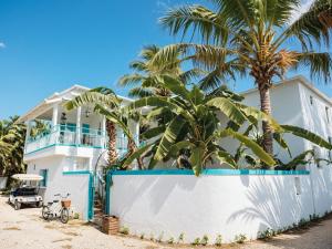 a white house with palm trees in front of it at SunSeaSurf Maldives in Thulusdhoo