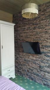 ein Schlafzimmer mit einem TV an einer Steinmauer in der Unterkunft Zhaily Sai Resort, in Zhezdi