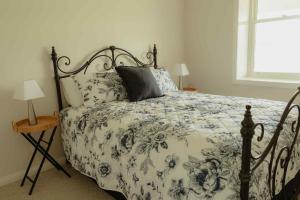 a bedroom with a bed with a blue and white comforter at Cosy 2 bedroom cottage with rural farmland views in Ross Creek