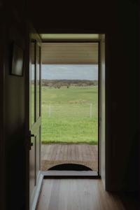 an open door with a view of a green field at Cosy 2 bedroom cottage with rural farmland views in Ross Creek