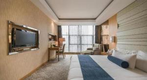寧波市にあるNingbo East Shipu Hotelのベッドと薄型テレビがあるホテルの部屋