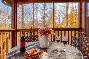 a table with a vase of flowers and two glasses of wine at Along the Trail Cabin with Hot Tub Pool Pond Game Room in Wear Valley