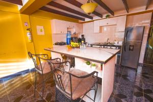 une cuisine avec des murs jaunes et un comptoir avec des chaises dans l'établissement Posada Yeskol, à San Andrés