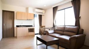 a living room with a couch and a kitchen at B2 Amata Nakorn Premier Hotel in Ban Chak Samo