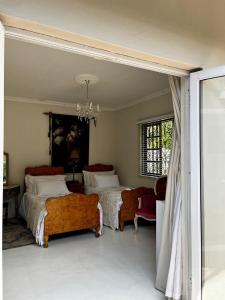 a bedroom with two beds and chairs and a window at Pepper Tree Guesthouse in Bloemfontein