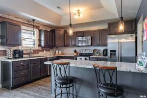 a kitchen with wooden cabinets and a island with bar stools at Spacious Home with Pool book your stay! in Marion