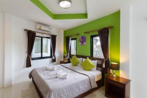 a bedroom with a bed with green walls at Samed Big Tree in Ko Samed