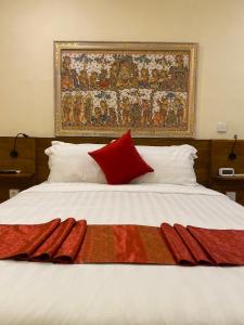 a bed with red pillows and a tapestry on the wall at Bali Emerald Apartments in Sanur