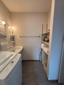 a white bathroom with a sink and a tub at 一棟貸切の民宿 月 駐車場2台無料 バス停徒歩1分 市街地へ好アクセス in Matsuyama +20 photos