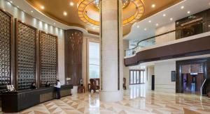 Un vestíbulo de un hotel con un hombre de pie en un mostrador. en Venus Royal Hotel Guangdong Meizhou Huangjia Mingdian, en Meizhou
