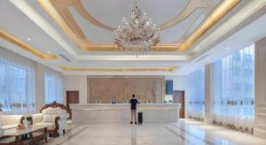 a person standing in a lobby with a chandelier at Vienna Hotel Guizhou Hezhang in Hezhang