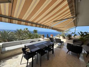 アデへにあるMarazul Sunsetのテーブルと椅子があり、海が見えるパティオ