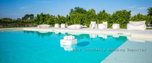 una piscina con acqua blu e cuscini bianchi di Hotel Ristorante al Gabbiano a Ponte di Piave