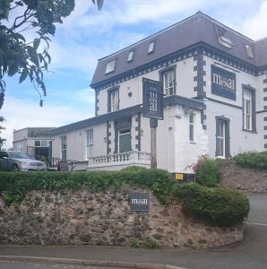 a large white building with a sign in front of it at The Menai Hotel and Bar in Bangor