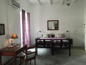 a room with two beds and a table and a desk at Villa Helena in Pondicherry