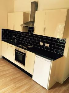 a kitchen with white cabinets and a black counter top at The Tudor House Hotel in Nottingham +106 photos