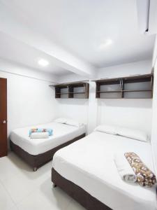 Dos camas en una habitación con paredes blancas. en Apartamentos Sophia Pb, en San Andrés