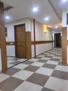a hallway with a checkered floor and wooden doors at Love kush hospitalitie in Ujjain