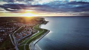 an aerial view of a beach with the sun setting over the water at Oesterbaai 36 in Wemeldinge