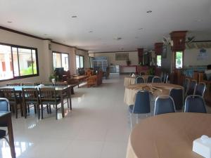 un comedor con mesas, sillas, mesas y sillas y un sillón en Chaleunehoung Hotel, en Ban Houadông