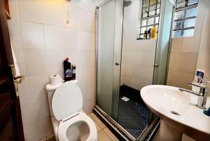 a bathroom with a shower and a toilet and a sink at Majestic Two-bedroom House in a prime location in Nairobi +3 photos