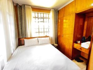 a bedroom with a white bed and a window at Majestic Two-bedroom House in a prime location in Nairobi