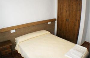 a small bedroom with a bed with a wooden headboard at Apartamentos La Palmera in Conil de la Frontera +8 photos