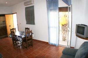 a living room with a table and chairs and a tv at Apartamentos La Palmera in Conil de la Frontera