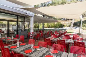 un restaurant avec des chaises rouges, des tables et des parasols dans l'établissement Hôtel de l'Arbois, à Aix-en-Provence