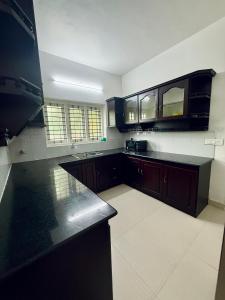 Una cocina con gabinetes negros y una encimera negra. en Zenaura Casa Villa 2, en Kochi