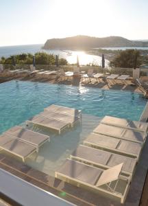 a swimming pool with lounge chairs and the ocean at Hotel Cala Moresca in Bacoli